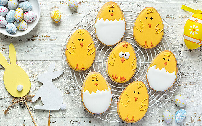 A set of cute, decorated cookies shaped or designed like baby chicks, covered in colorful icing, typically made for Easter.