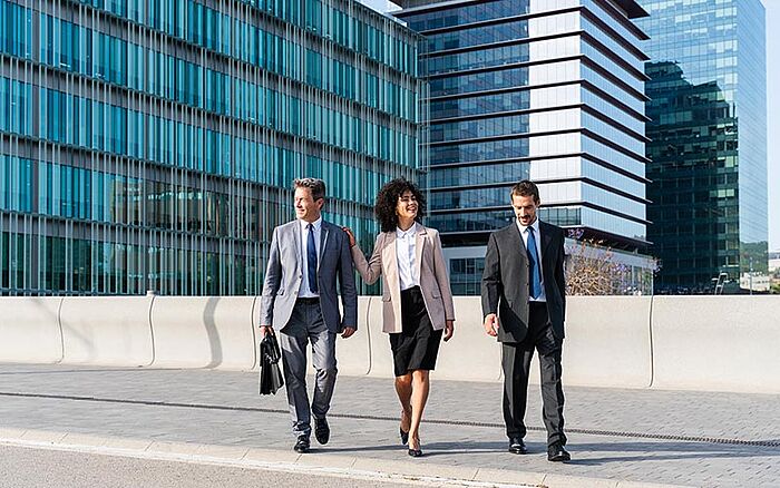 A group of three multiracial professionals leaves work after a successful day.