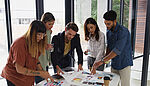 Creative agency staff at a boardroom table holding a colour swatch palette, discussing company branding and design strategy together.