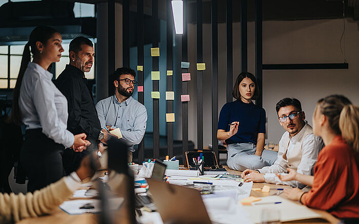 A group of professionals gathered around a table in a modern office, sharing ideas in a lively, collaborative discussion.