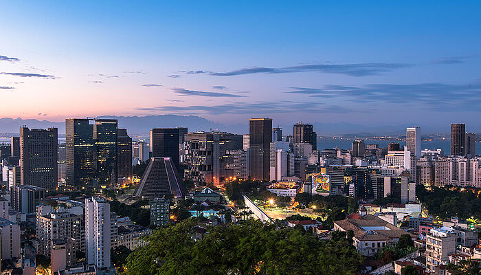 Financial district of Rio de Janeiro at sunset, with modern high-rise buildings and warm evening light reflecting off the skyline.
