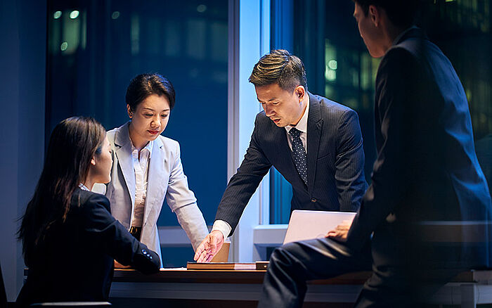 Asian team working on a project in the office at night