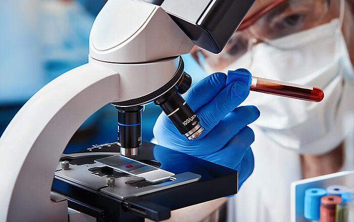 A scientist examines a blood sample under a microscope in a laboratory, with a focus on the new strain of the coronavirus, during research related to COVID-19.