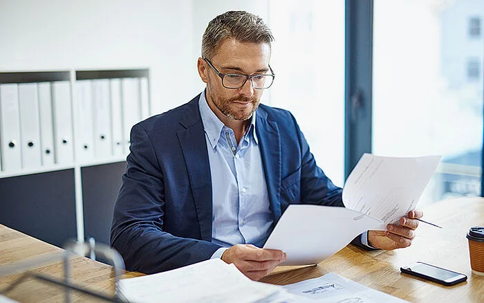 Business man sitting at his desk, reviewing a trademark application. 