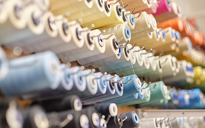 A group of large multicolored sewing thread spools arranged in a bunch at an atelier workshop. 