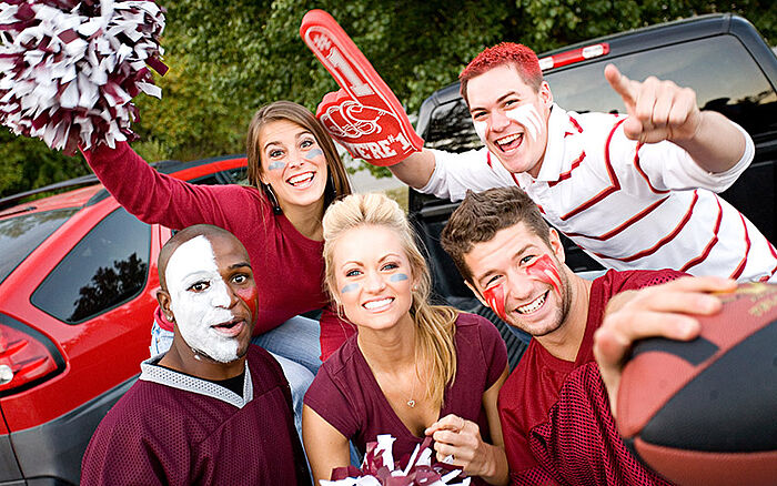 Cheerful college friends gathered outdoors in team colors before a football match.