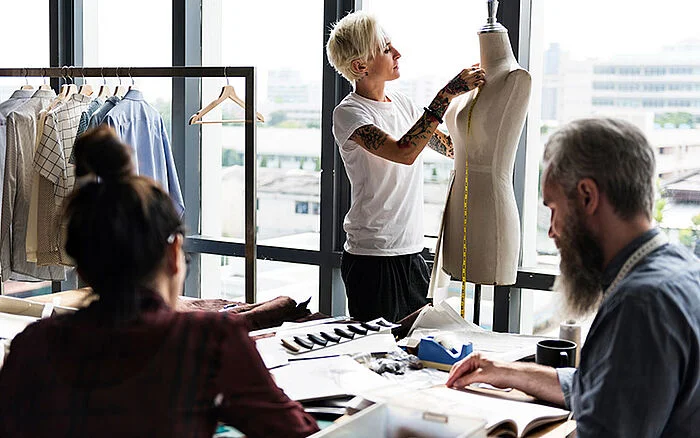 A tailor's mannequin draped with measuring tape stands in a design studio, symbolizing the precision and creativity involved in fashion design.