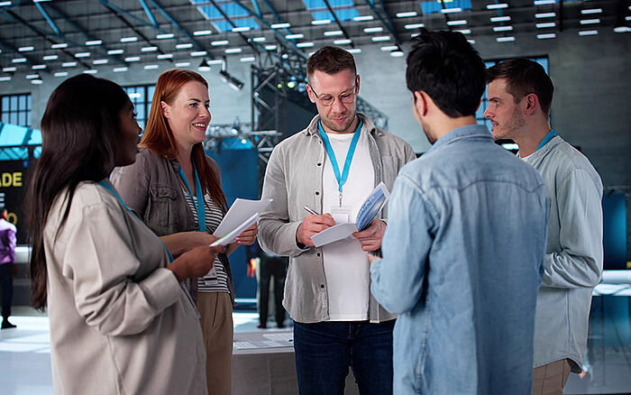 A man presenting new technology to a diverse group of colleagues standing together.