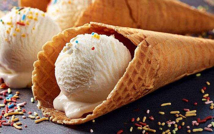 Vanilla ice cream scoops in waffle cones with sprinkles