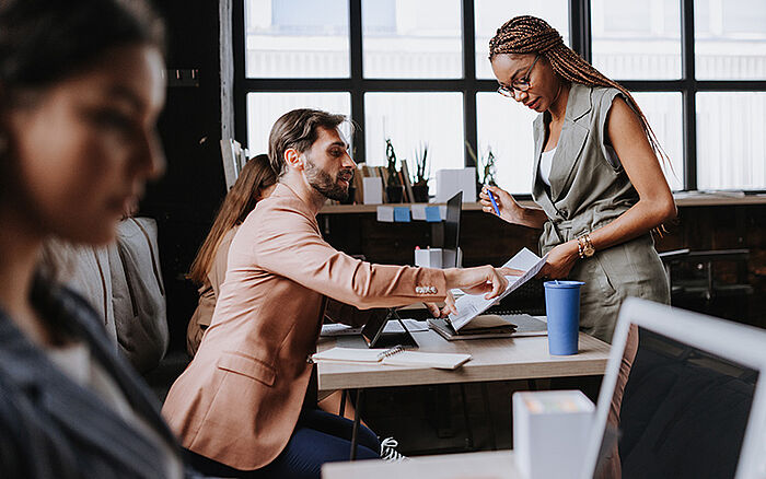Group of freelancers and remote professionals collaborating and sharing ideas in a modern coworking space, discussing a business project in a relaxed, open-plan environment.