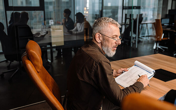 Mature professional reviewing documents during a discussion in a modern office.
