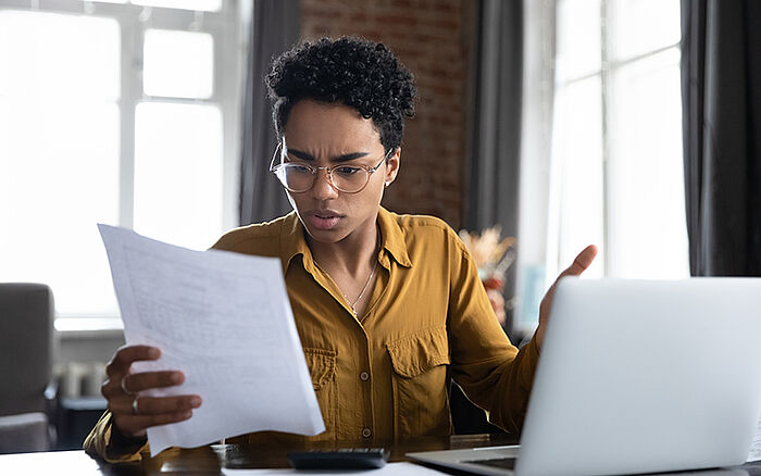 Concerned woman reading a document with distress, reacting to unexpected or negative news.