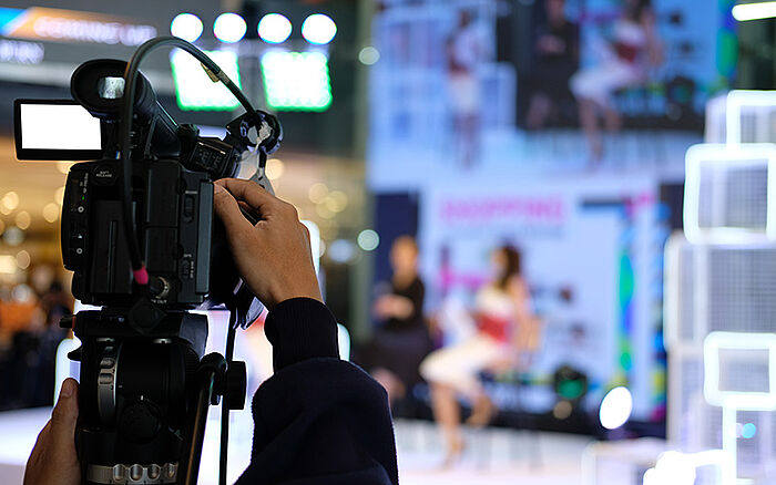 Professional video camera recording a live stage event, used for television and social media broadcasting of a conference.